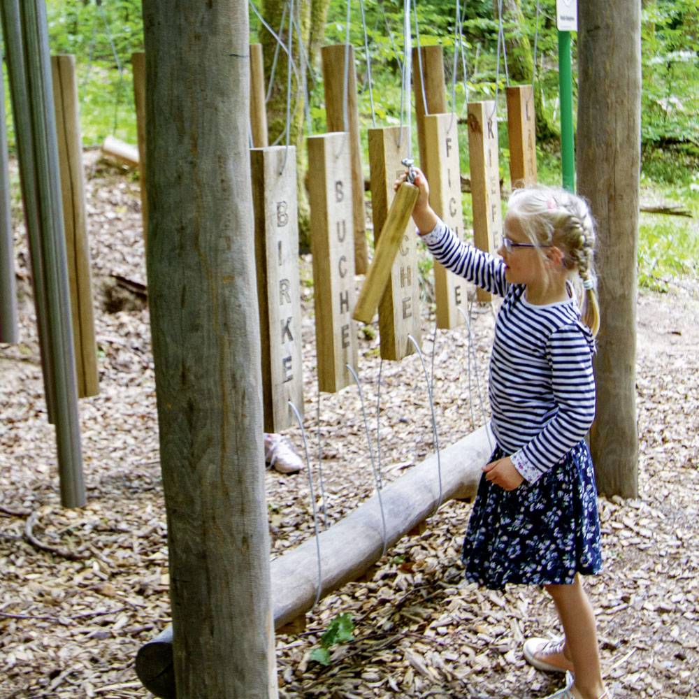 Mädchen spielt auf einem Holz-Xylophon aus Baumteilen