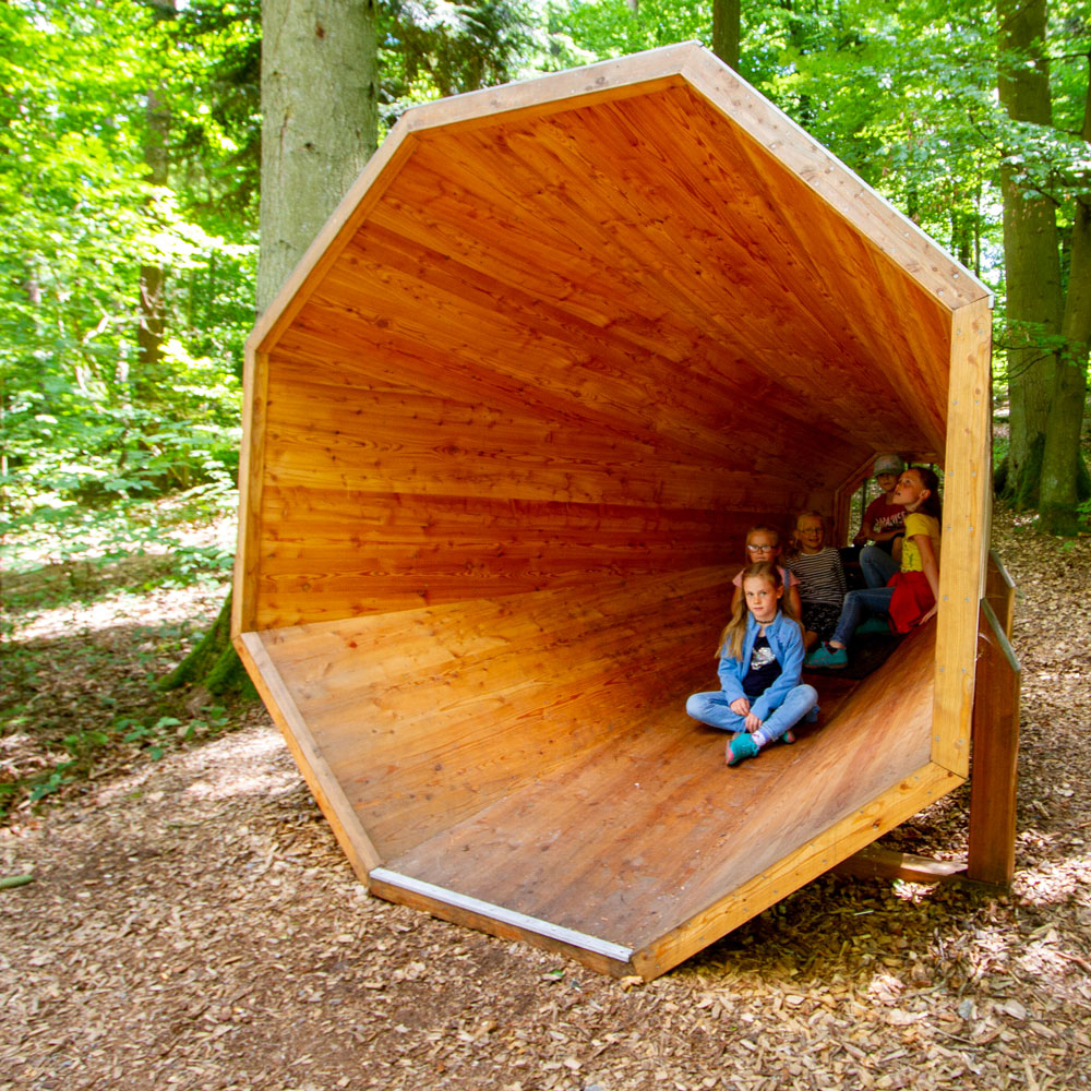 Kinder sitzen im Hörtrichter des Waldlehrpfades